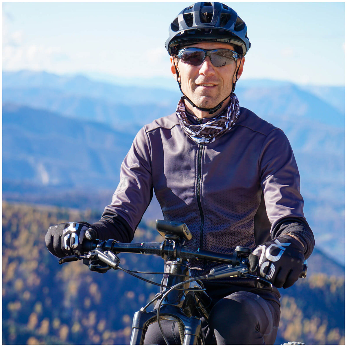 Ein Radfahrer mit Helm und Sportbrille vor einem Bergpanorama.