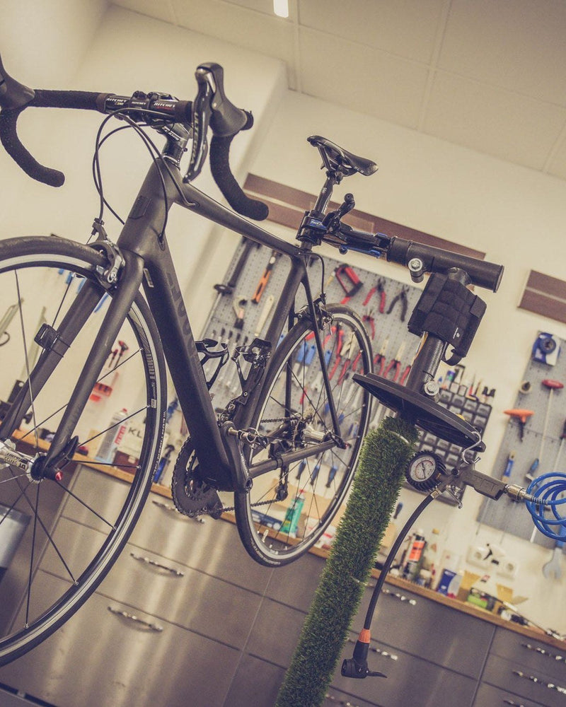 Ein Rennrad steht in einer Werkstatt vor einer Wand mit Werkzeug.