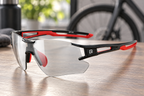 Sportbrille rahmenlos Schwarz/Rot – Detail auf einem Holztisch