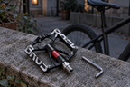 Aluminium-Plattformpedal – auf einer Steinmauer neben einem Fahrrad in der Abenddämmerung