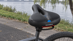 Komfortsattel mit Memory-Schaum – schwarzer Sattel mit blauen Details auf einem Fahrrad am See